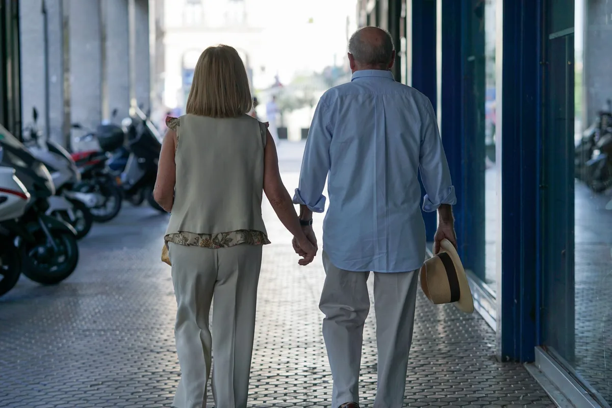 Senior couple walking hand in hand down a sidewalk